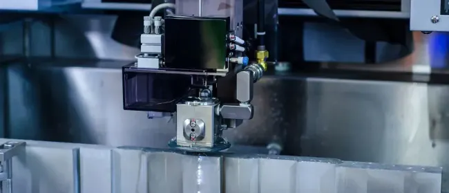 Una máquina está cortando un trozo de metal en una fábrica.