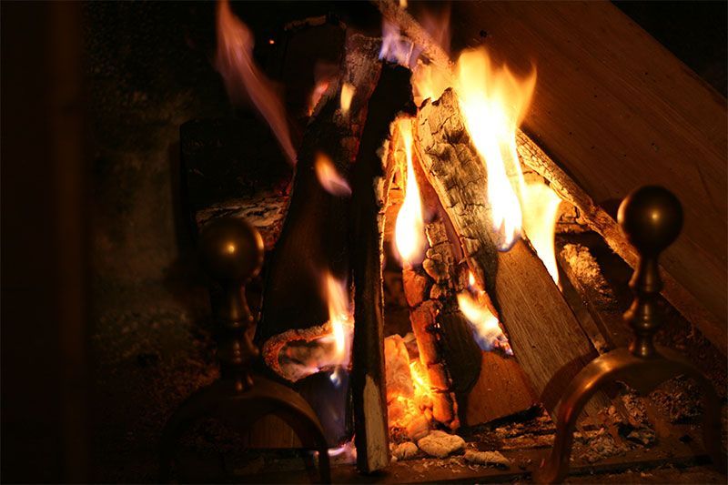 Cheminée flamboyante, bûches incandescentes, flammes et chevrotines métalliques. Tons chauds.