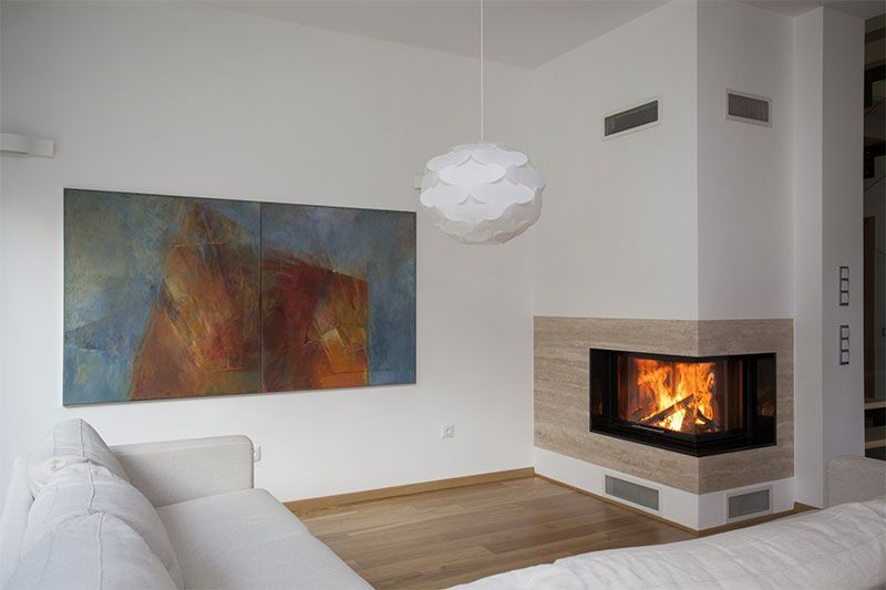 Salon chaleureux avec cheminée, art abstrait, canapé blanc et luminaire moderne.