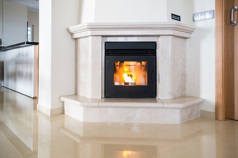 Cheminée avec un feu allumé dans un entourage en marbre, dans une maison moderne au sol brillant.