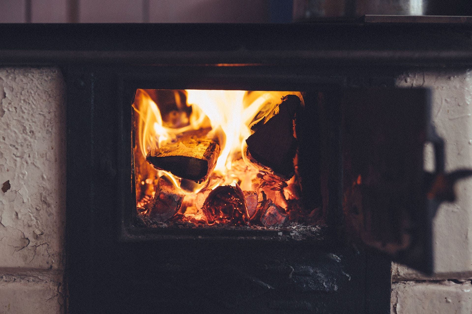 Un feu brûle vivement dans un poêle à bois dont la porte est ouverte.
