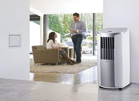 Un homme et une femme près d'un climatiseur. Ils sont à l'intérieur, près d'une fenêtre.