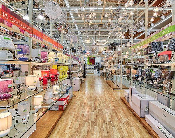 Intérieur d'un magasin de luminaires présentant diverses lampes sur des étagères. Lumineux grâce à son parquet et ses éclairages au plafond.