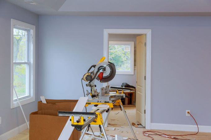 Habitación en proceso de renovación con sierra ingletadora, cajas y herramientas en un interior de paredes azules.