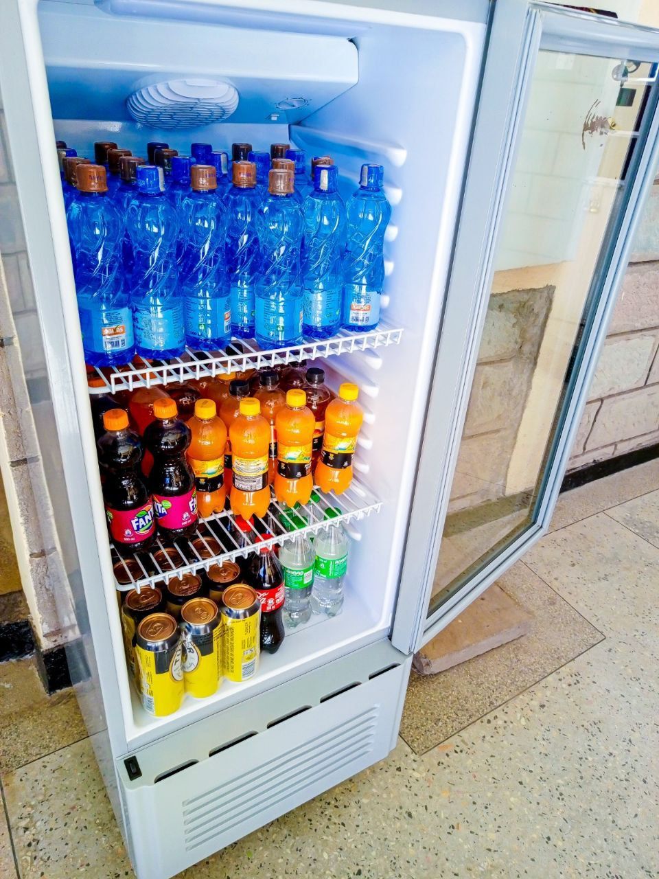 A refrigerator filled with bottles and cans of soda