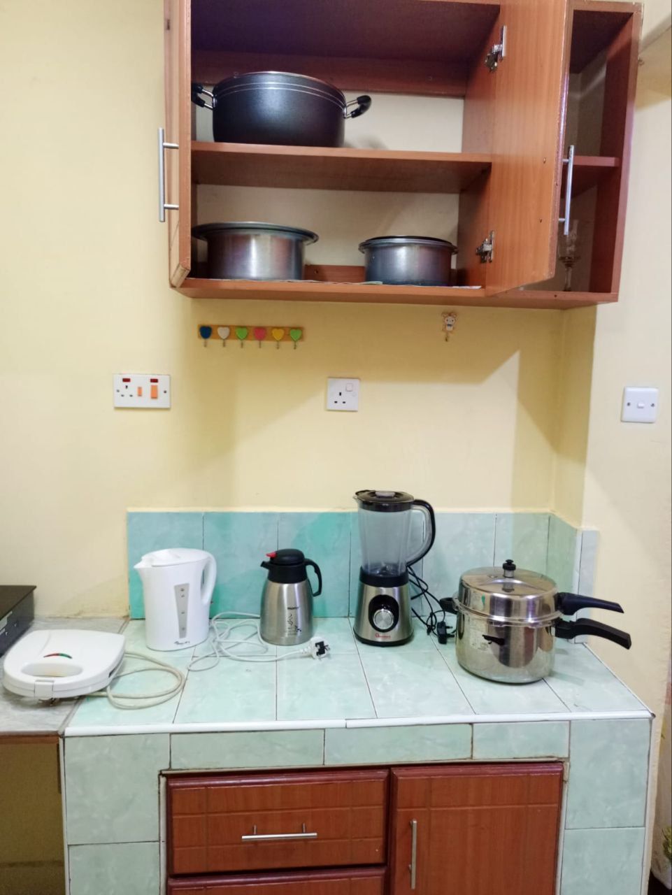 A kitchen with a blender , pots and pans on the counter.