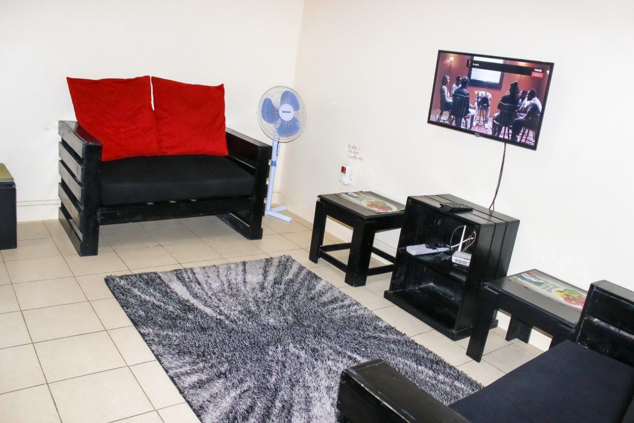 A living room with a couch , chairs , tables and a flat screen tv.