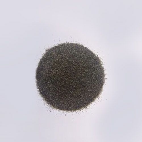 Montón de arena gris oscuro sobre una superficie blanca.