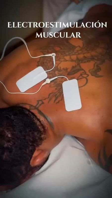 Hombre recibe tratamiento de electroestimulación muscular en la espalda, con almohadillas y cables conectados.