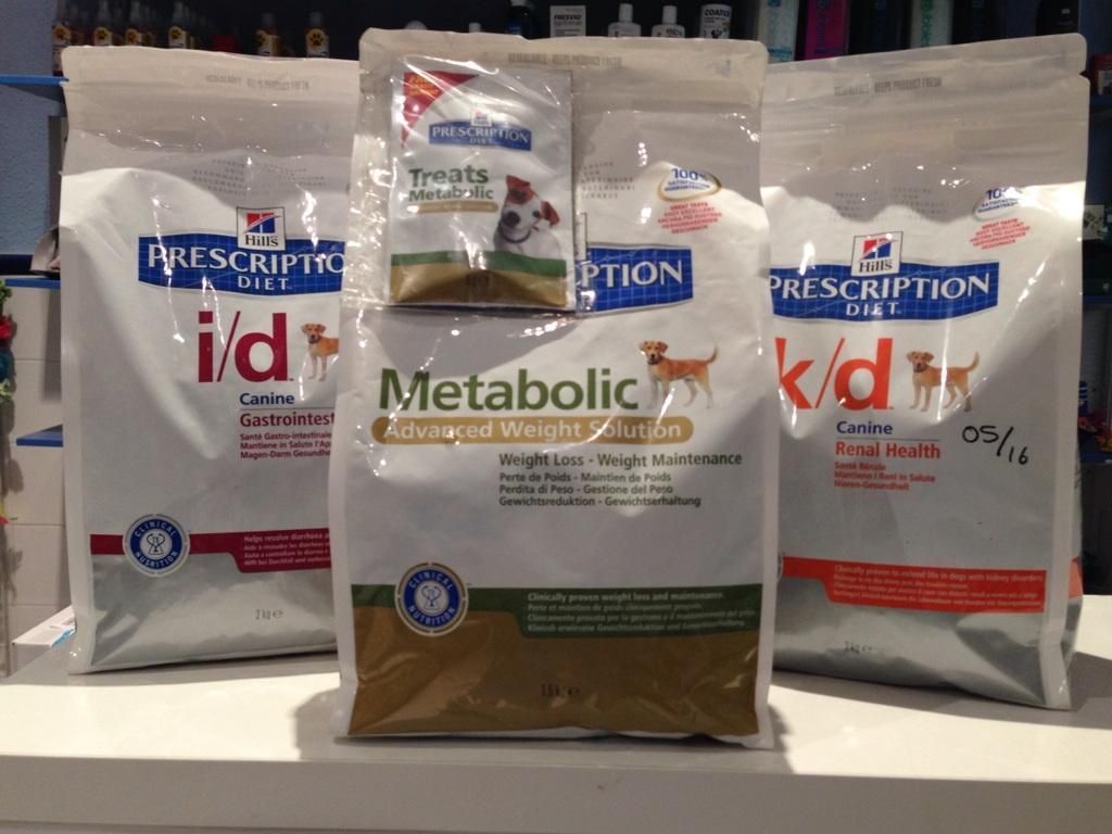 Tres bolsas de comida dietética recetada para perros están sobre un mostrador.