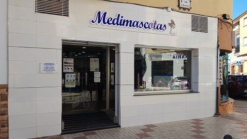Un edificio blanco con un cartel azul que dice medinamascotas.