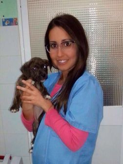 Una mujer con un uniforme azul sostiene un cachorro