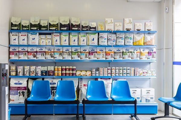 Una sala de espera con sillas azules y estantes llenos de comida para mascotas.