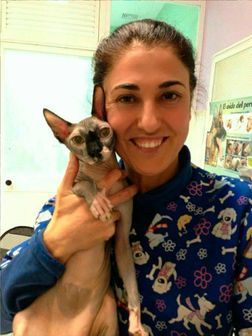 Una mujer sostiene un gato en sus brazos y sonríe.