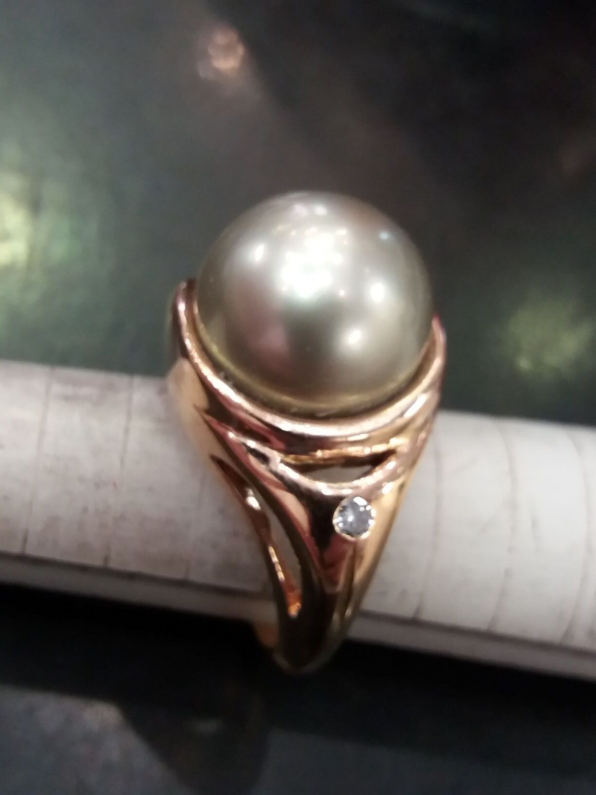 Une bague en or avec une petite pierre et une boule au milieu.