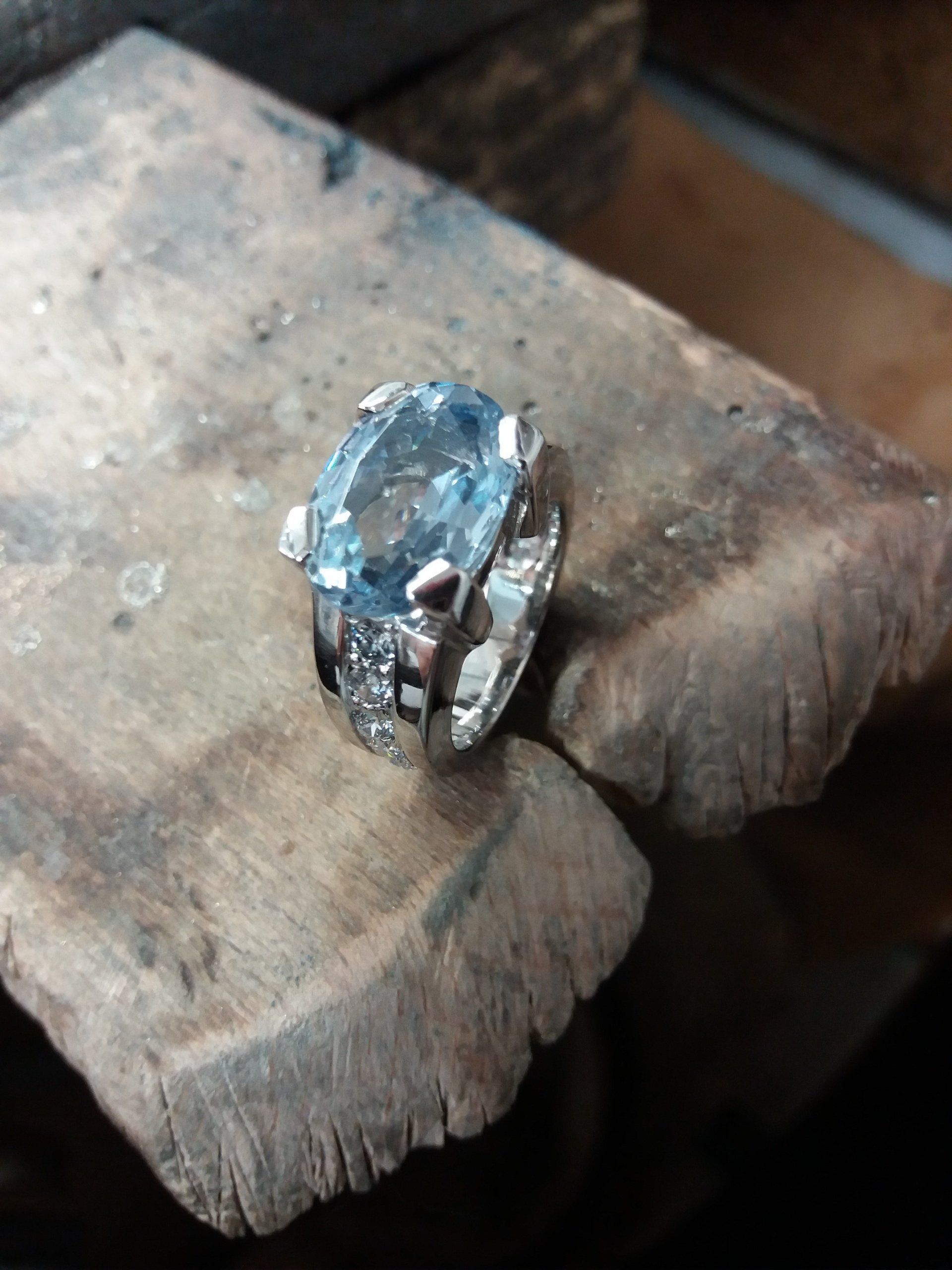 Une bague grise avec une pierre bleue, entourée de diamants.
