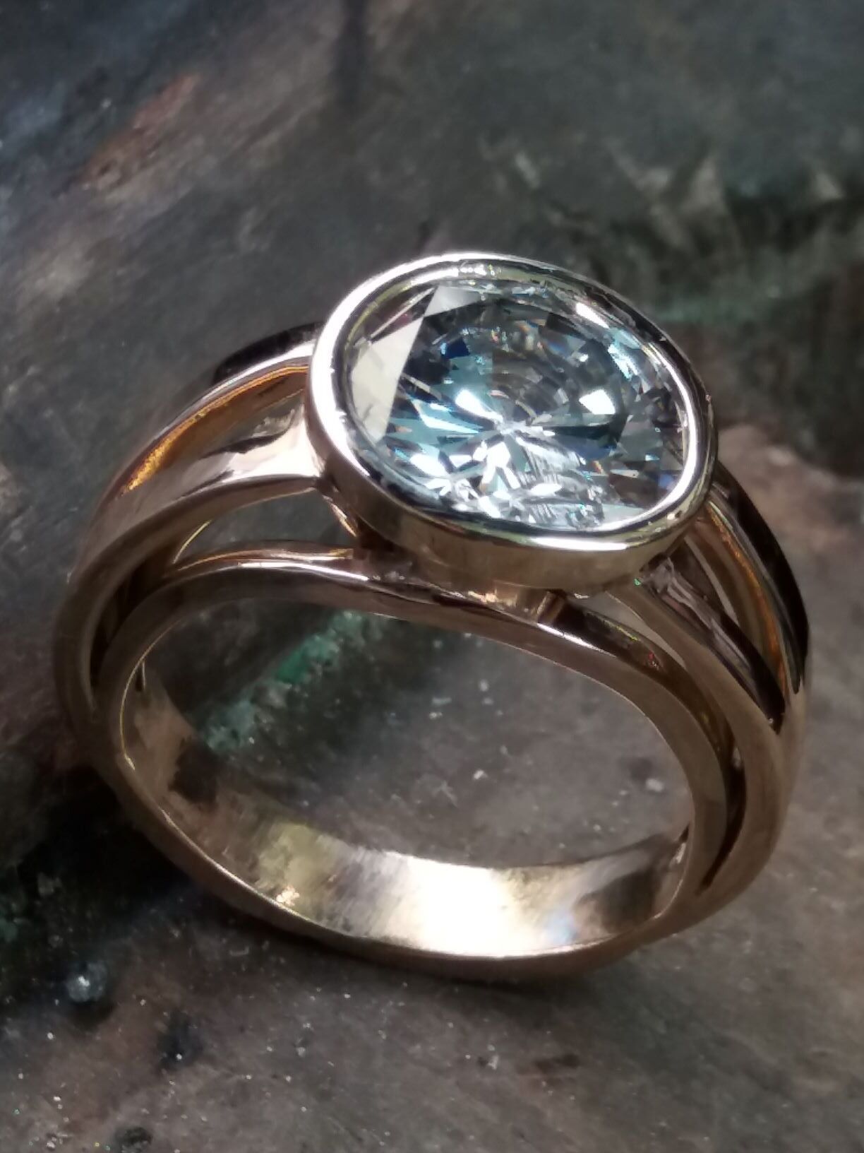 Une bague en or avec une pierre brillante dessus.