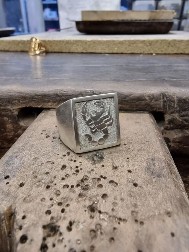 Une chevalière avec un scorpion au milieu.