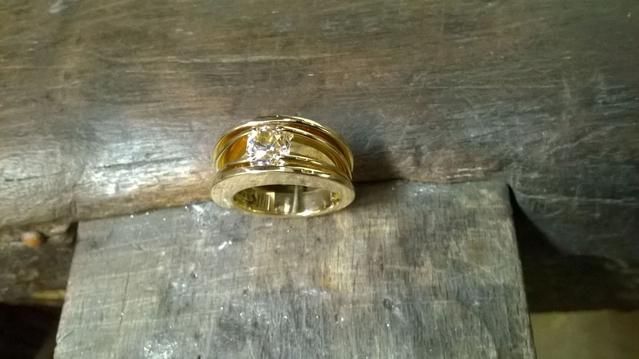 Une bague en or avec une pierre blanche au milieu.