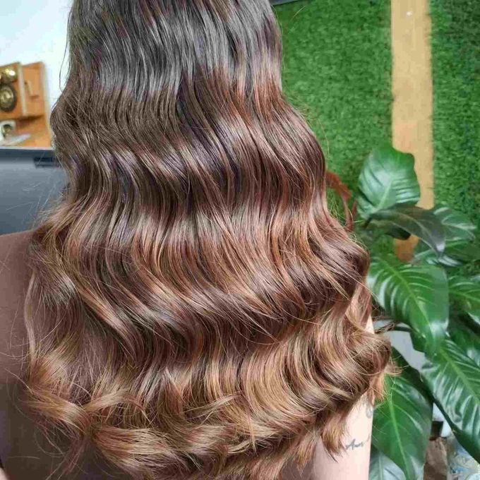 Cabello castaño ondulado con reflejos color caramelo