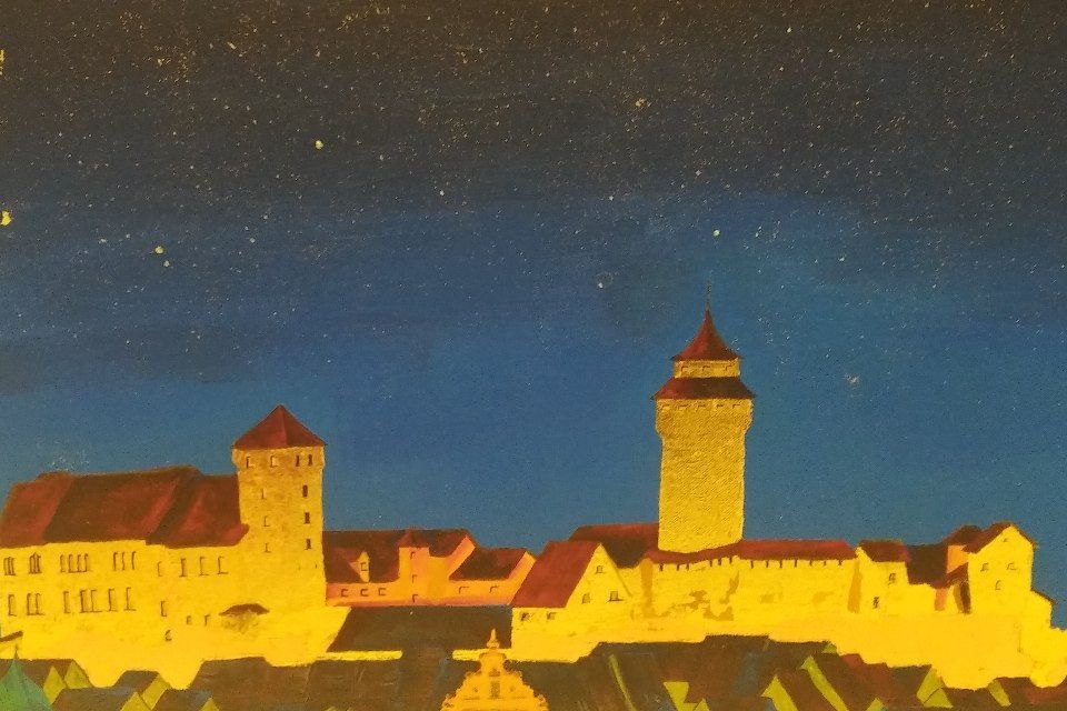 Eine Burg, die sich vor einem dunkelblauen Nachthimmel mit verstreuten Sternen abzeichnet; beleuchtet von gelben Lichtern.