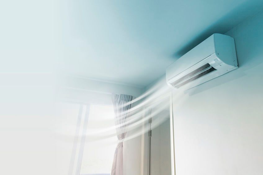 Una habitación con un aparato de aire acondicionado montado en el techo que expulsa aire por una ventana.