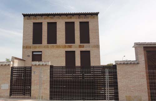 Un edificio de ladrillo con una valla a su alrededor y una puerta corrediza.