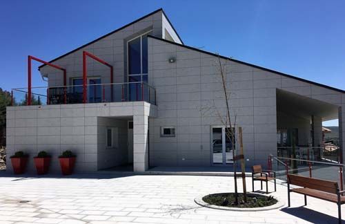 Una gran casa blanca con un balcón y un banco delante de ella.