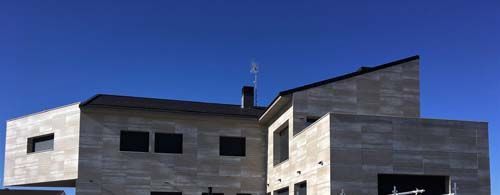 Una gran casa de ladrillos está en construcción con un cielo azul en el fondo.