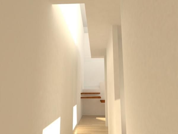 Un pasillo con escaleras y una luz que entra por el techo.