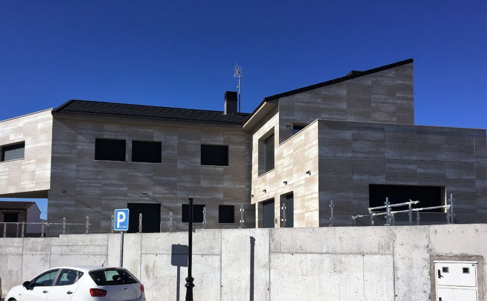 Un coche blanco está aparcado delante de una casa grande.