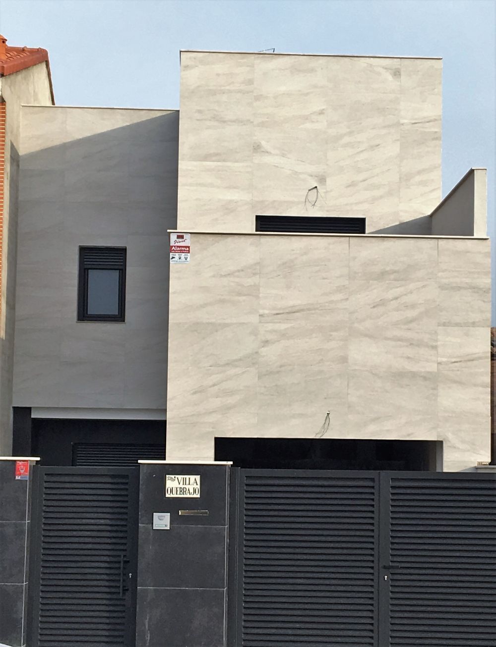 Un edificio blanco con una valla negra delante.