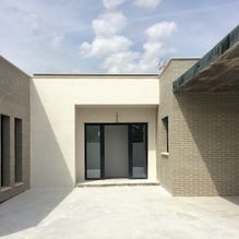 Una casa blanca con una gran ventana y un patio delante de ella.