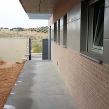Un edificio de ladrillo con una pasarela de hormigón y muchas ventanas.