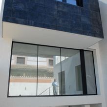 Un hombre está parado en el balcón de un edificio con muchas ventanas.