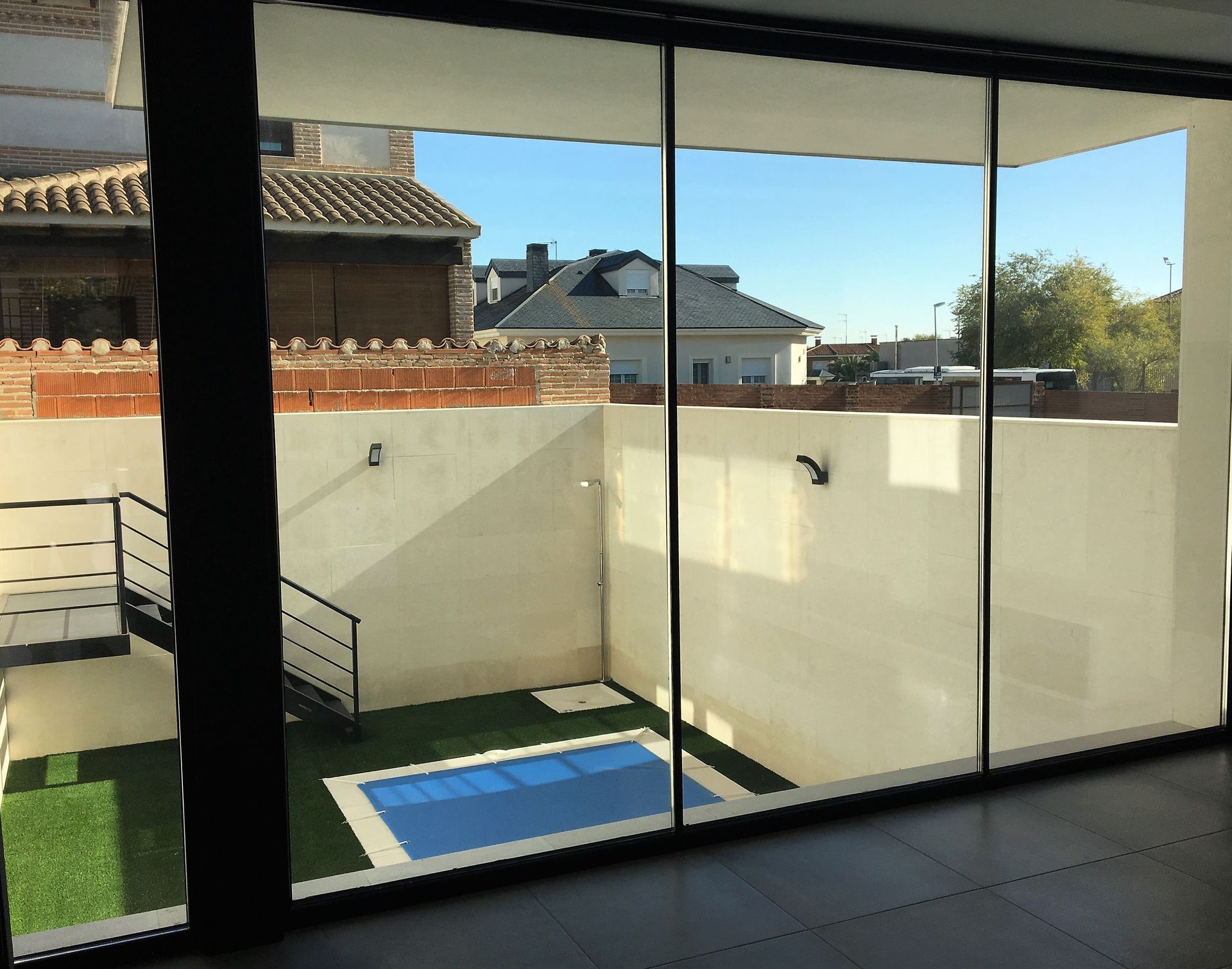 Una vista de una piscina a través de una puerta corrediza de vidrio.