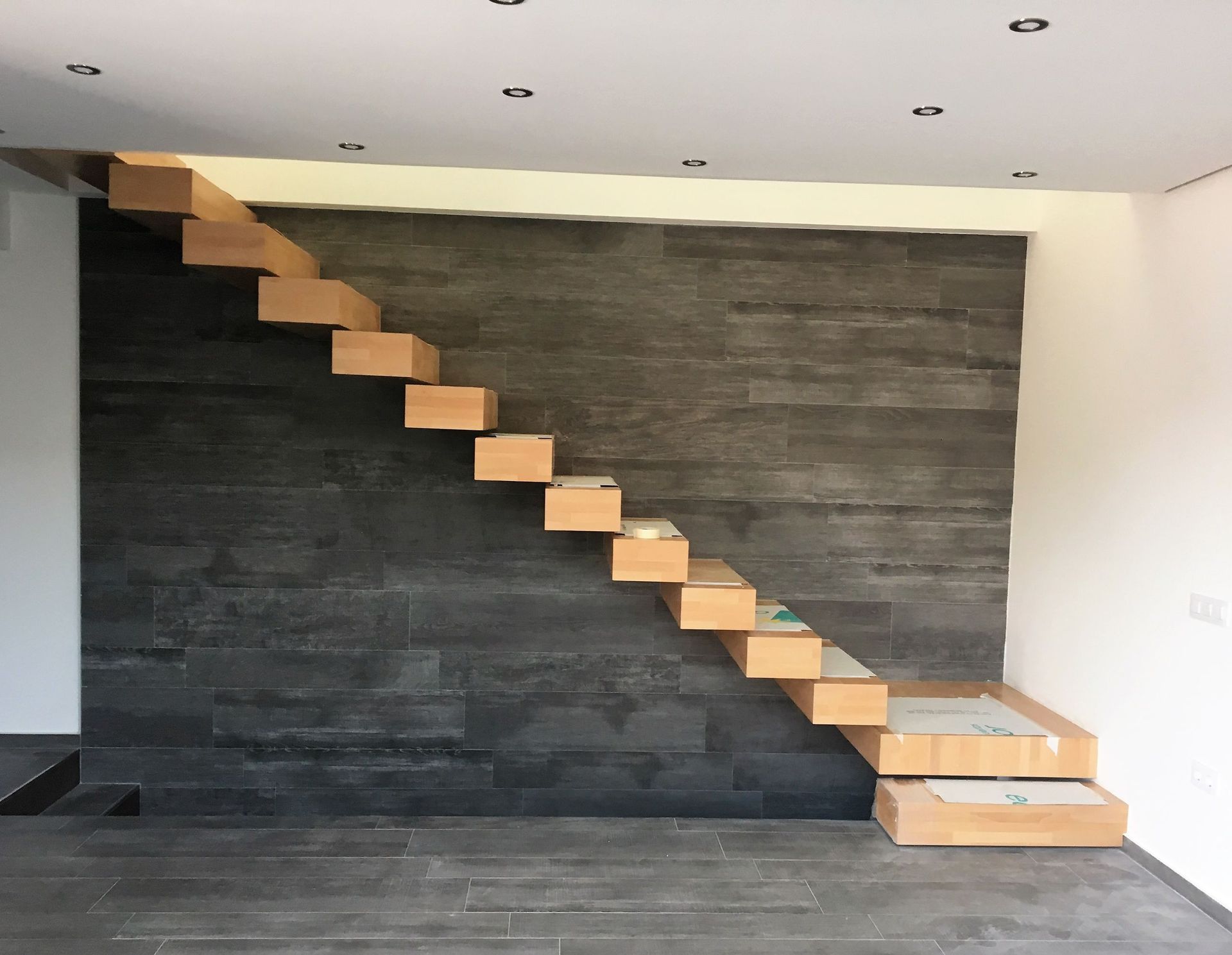 Una escalera de madera con una pared negra detrás.