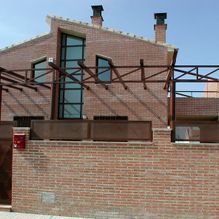 Una casa grande de ladrillo con valla y balcón.