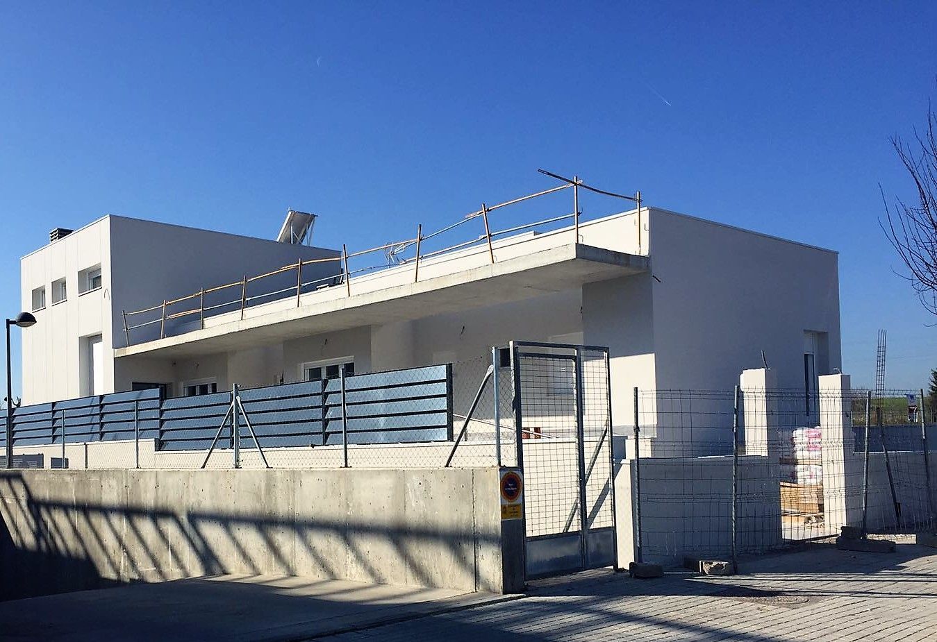 Un edificio blanco con una valla azul a su alrededor y un cielo azul de fondo.