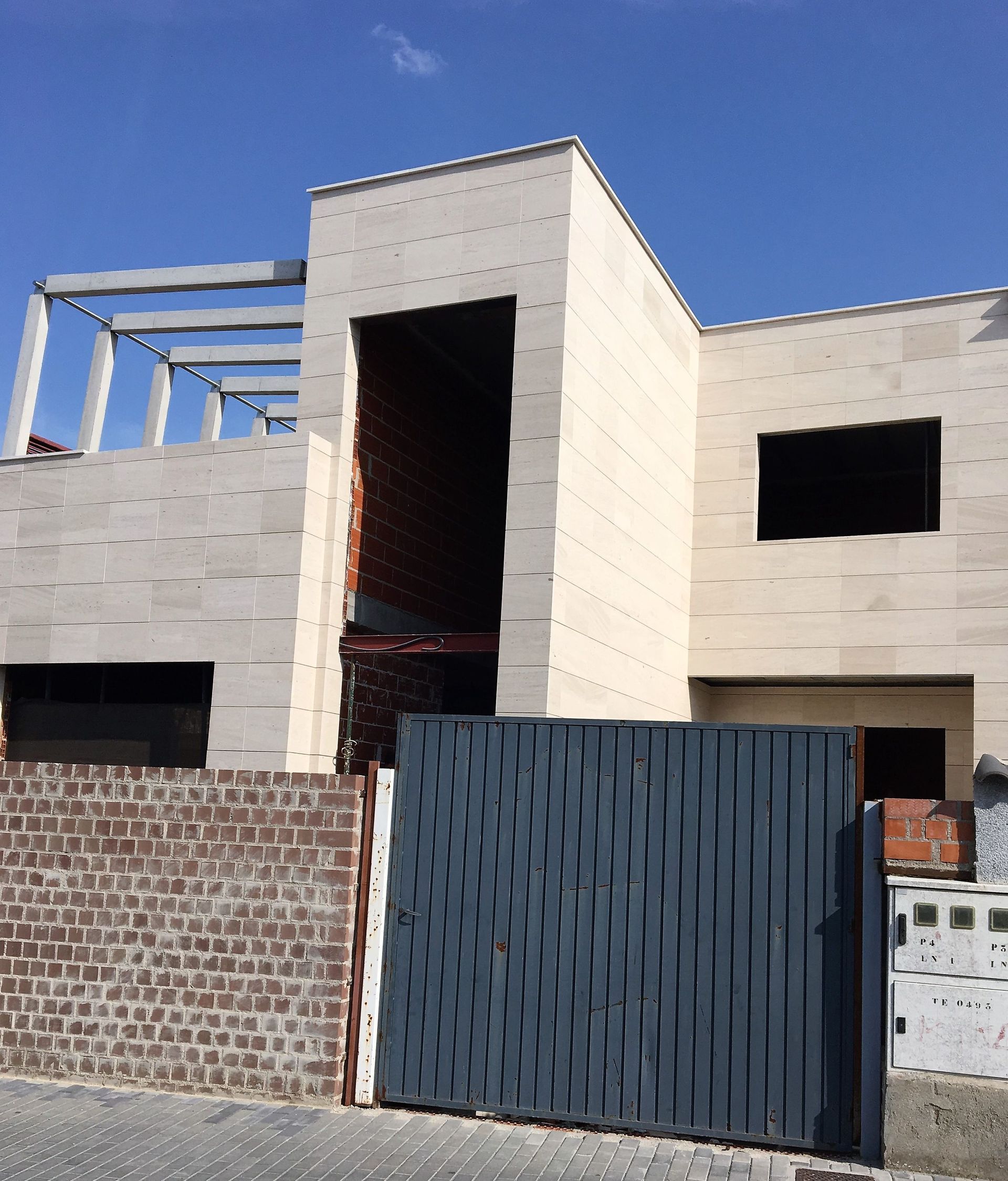 Un edificio en construcción con una valla azul delante.