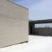 Un edificio de ladrillo blanco con una entrada de hormigón delante.