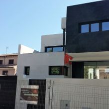 Una casa grande de color blanco y negro con una valla delante.