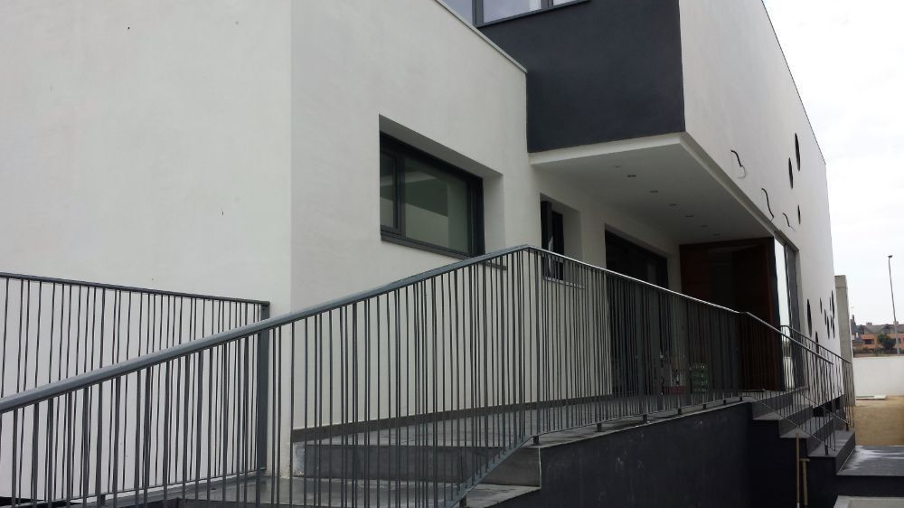 Un edificio blanco con una barandilla negra y escaleras que conducen a él.