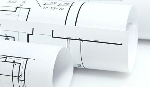 Tres rollos de dibujos arquitectónicos sobre una superficie blanca.