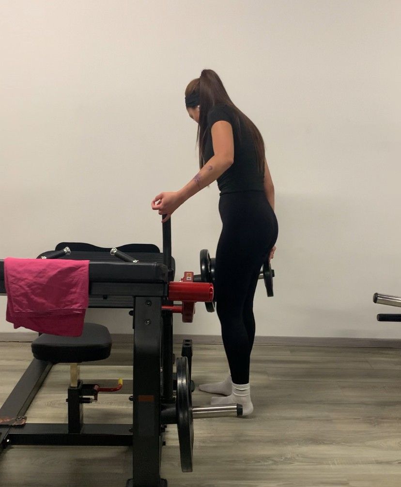 Une femme se tient à côté d'une machine dans une salle de sport