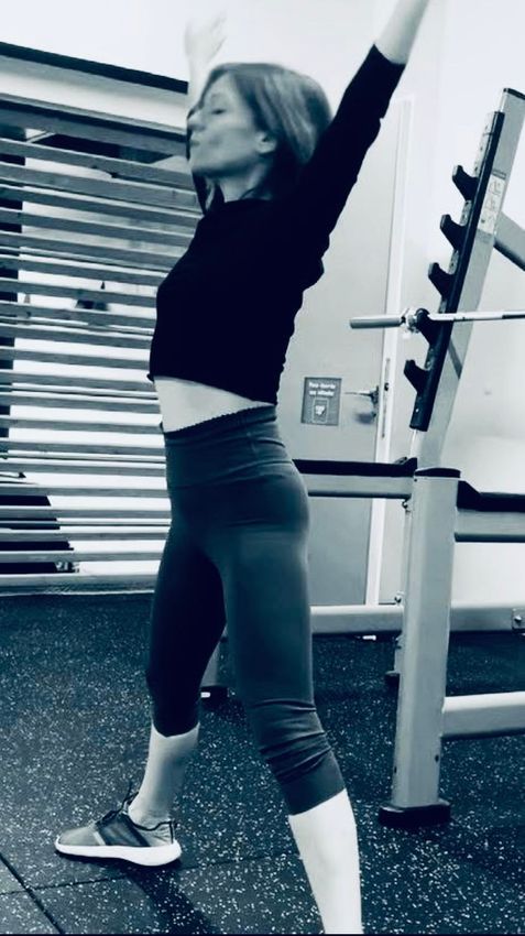 Une femme en chemise orange fait une pose de yoga dans une salle de sport