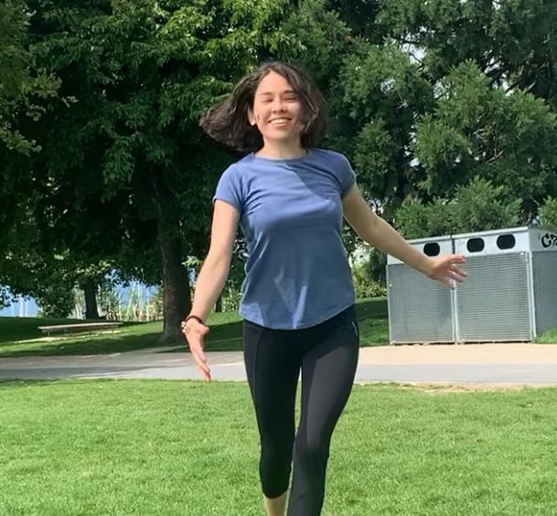 Une femme fait le poirier dans une salle de sport pendant qu'une autre femme regarde.