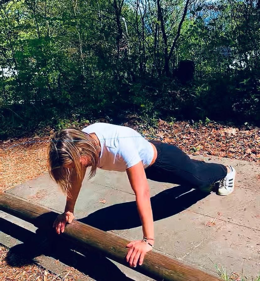 Une femme fait des pompes sur une barre en bois