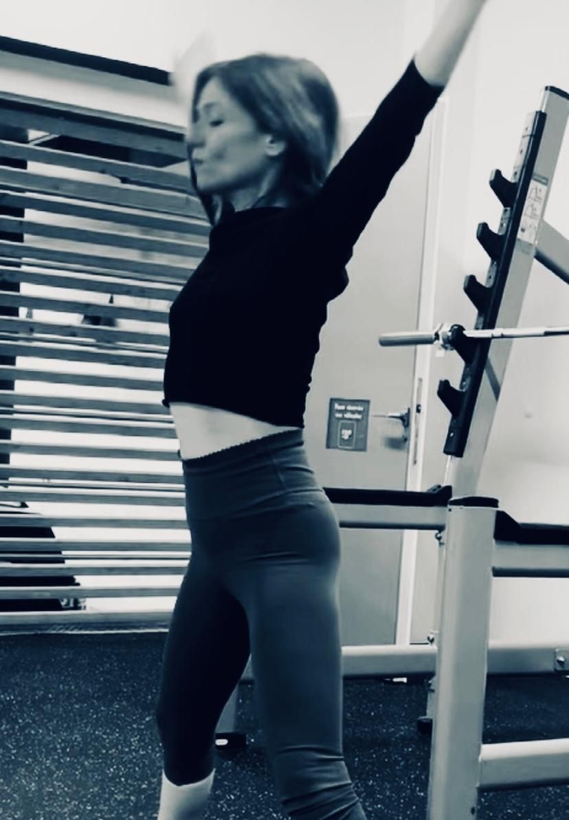 Une femme en chemise orange fait une pose de yoga dans une salle de sport