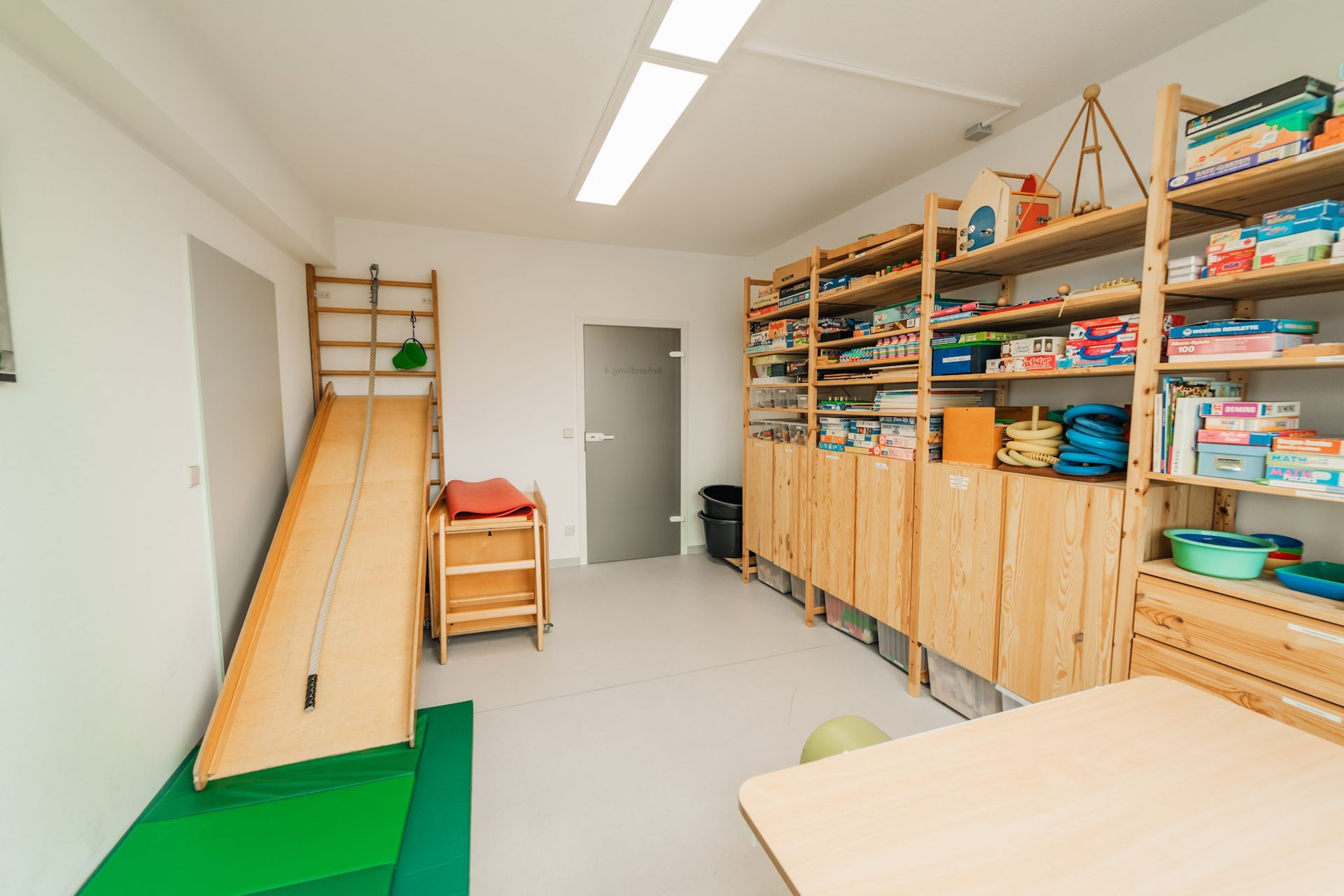 helles Zimmer mit einem Holzregal mit verschiedenen Utensilien, eine Holzrampe